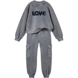 Love Paillette Tekst Strijk Embleem Patch op de sweater van een grijs joggingpak