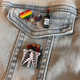 Skelet Geraamte Ribben Bloemen Emaille Pin samen met drie andere pins op een spijkerjasje