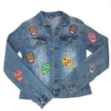 Multicolor Sugar Skull Strijk Patch Set met acht sugar skulls scht verschillende kleuren op een blauw spijkerjasje