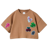 Girl Power Vuist Vrouwen Symbool Strijk Embleem Patch samen met andere strijk patches op een bruin kort shirtje