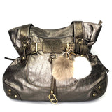 twee pompoms creme en taupe aan goudkleurige clips en sleutelhanger ringen en tekstplaatjes met de tekst megamooi aan een bronskleurige handtas