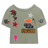 Girl Power Vuist Vrouwen Symbool Strijk Embleem Patch samen met andere strijk patches op een groen hemdje
