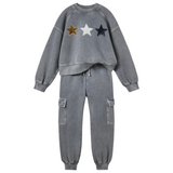 Ster Sterren Paillette Strijk Embleem Patch Zwart samen met de witte en goudkleurige variant op een grijs joggingpak