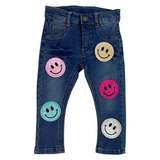 Smiley Emoji Strijk Embleem Patch Glitter Fuchsia Roze samen met de vier kleurvarianten op een kleine spijkerbroek