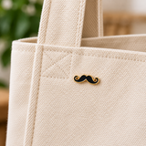 Snor Krulsnor Moustache Emaille Pin op een beige tas